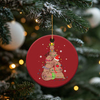 Red round ornament with capybara and nutcracker graphic, hanging on a Christmas tree