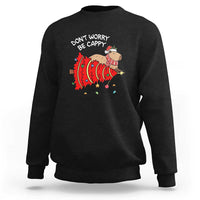 Black Christmas capybara sweatshirt with “Don’t Worry Be Capy” graphic on chest