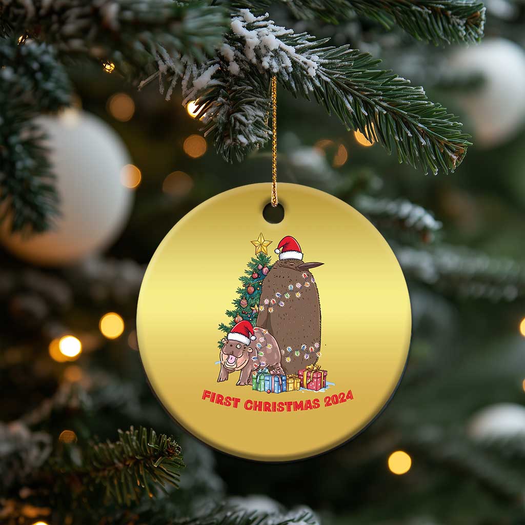 Gold round Christmas ornament hanging on a pine branch, cartoon nativity and 'First Christmas 2024'