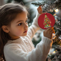 Child holding a red round Irish Christmas ornament with illustrated Christmas tree and shamrocks.