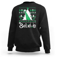 Black crewneck sweatshirt with festive 'Believe' print and green bow UFO graphic