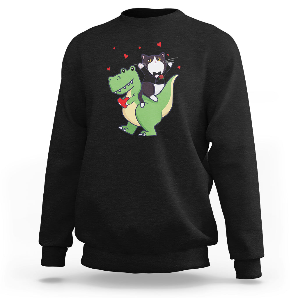 Black crewneck sweatshirt with cat riding green dinosaur holding rose graphic and red hearts