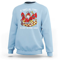 Light blue crewneck sweatshirt with colorful music-themed graphic and slogan on chest.