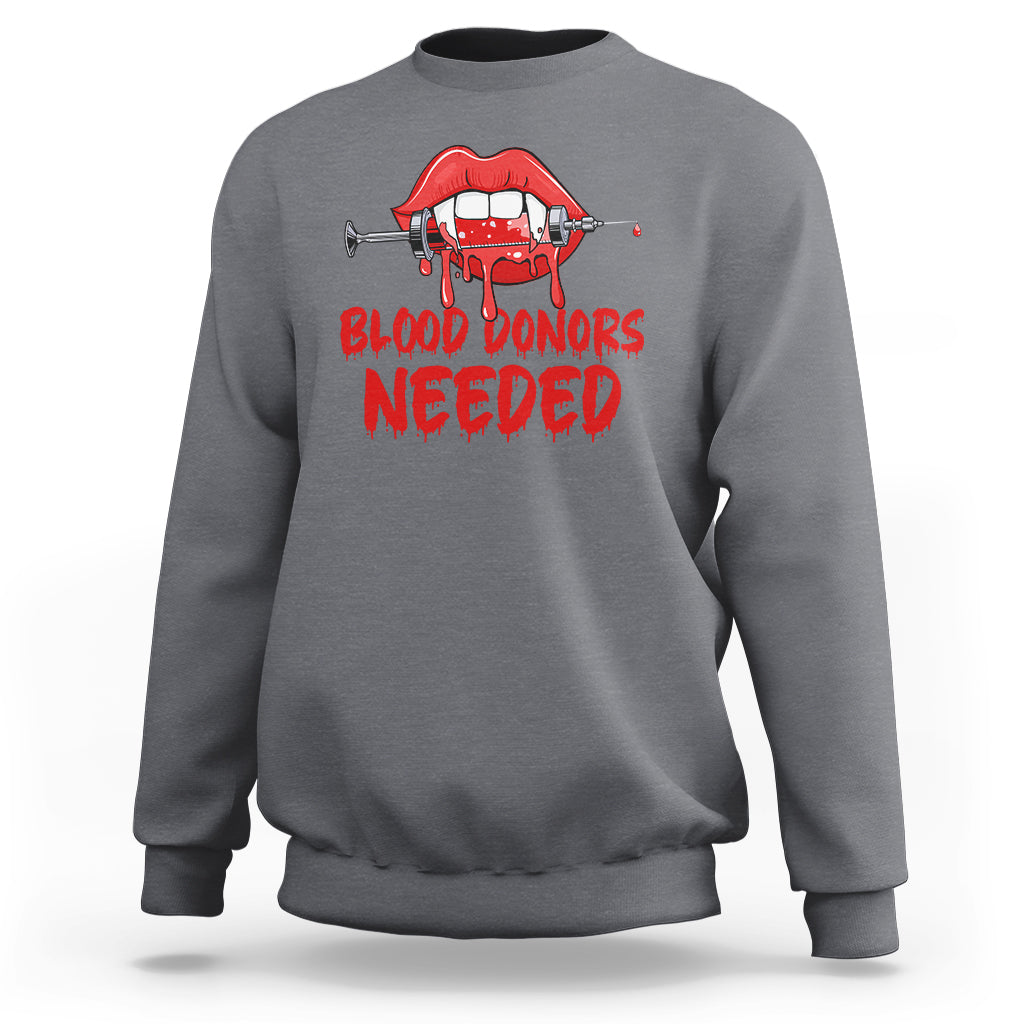 Charcoal crewneck sweatshirt with red vampire lip graphic and “BLOOD DONORS NEEDED” print