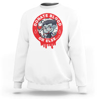 White crewneck sweatshirt with red vampire blood-donor graphic on the back.