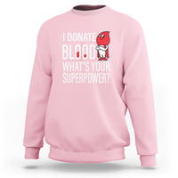 Light pink crewneck sweatshirt with front print: “I Donate Blood What’s Your Superpower?”