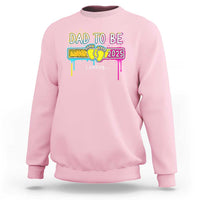 Light pink sweatshirt with “Dad to Be 2025” colorful loading graphic on front