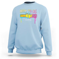 Light blue mom-to-be sweatshirt with colorful “Mom to be 2025” loading graphic on front