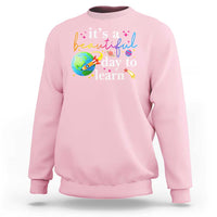 Light pink crewneck sweatshirt with "it's a beautiful day to learn" graphic