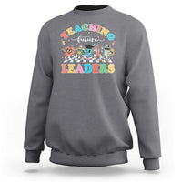 Charcoal gray teacher sweatshirt with colorful “Teaching Future Leaders” character graphic