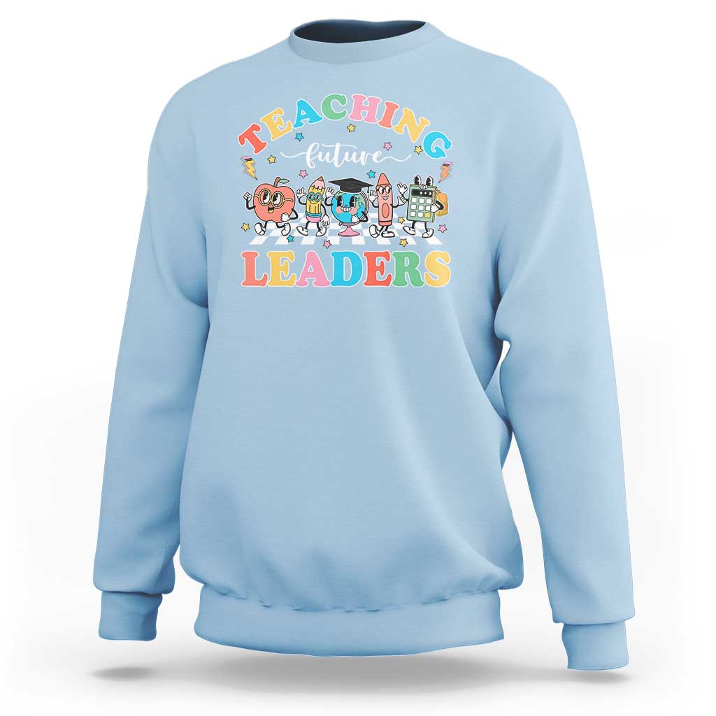Light blue teacher sweatshirt with colorful “Teaching Future Leaders” character graphic