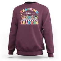 Maroon teacher sweatshirt with colorful “Teaching Future Leaders” character graphic
