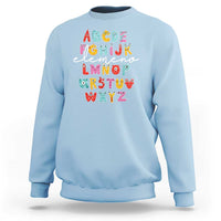 Light blue sweatshirt with cute monster alphabet A–Z graphic on front.