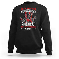 Black sweatshirt with front graphic text and Native American-style figures in red and white