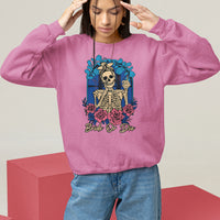 Light pink sweatshirt with front skeleton graphic, blue/red floral wreath print, relaxed fit