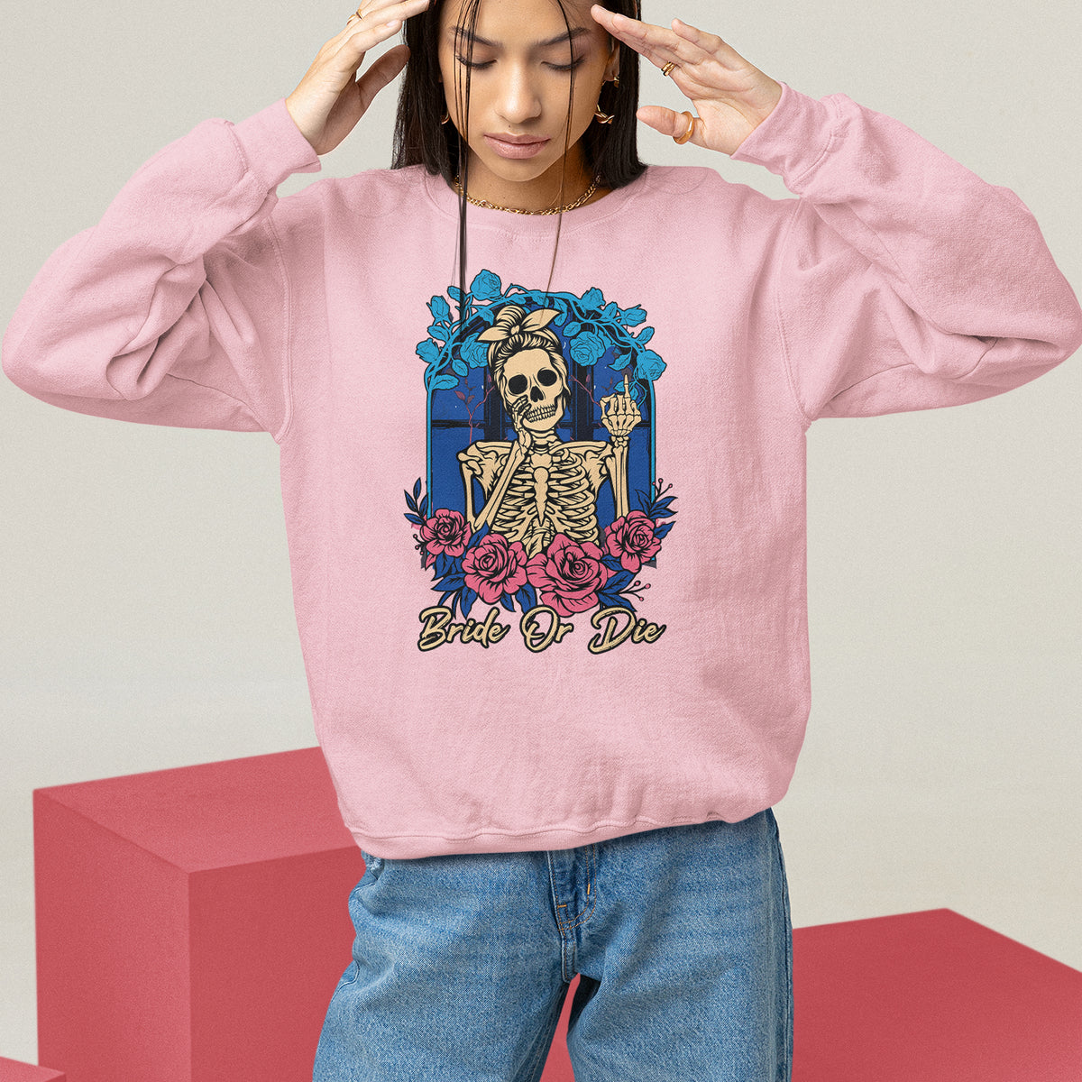 Light pink sweatshirt with front skeleton graphic, blue/red floral wreath print, crew neck