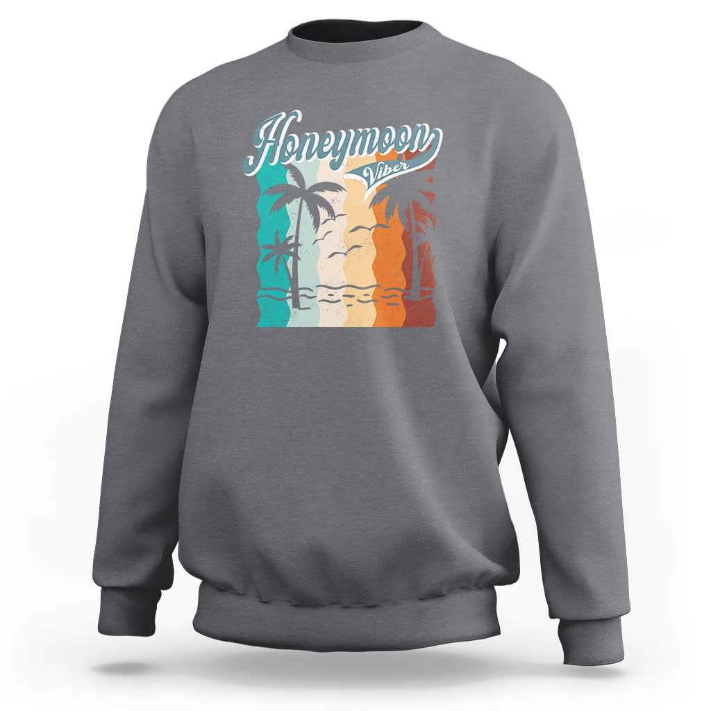 Charcoal gray crewneck sweatshirt with 'Honeymoon' beach graphic panel at chest