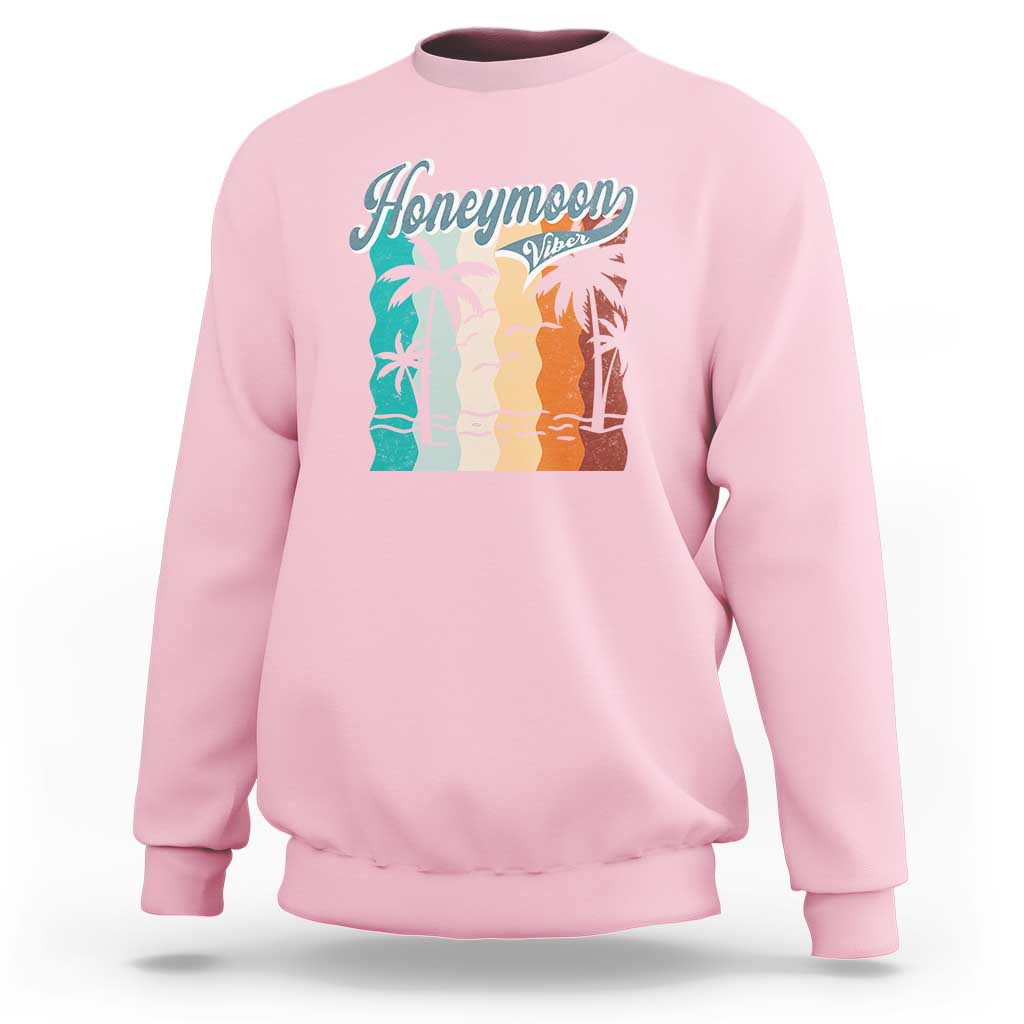 Light pink crewneck sweatshirt with 'Honeymoon' beach graphic panel at chest