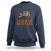 Blue crewneck sweatshirt with whiskey glass and cigar graphic; text 'I'll be in the backyard'.