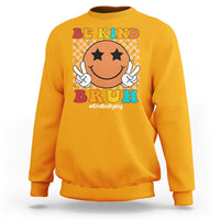 Orange crewneck sweatshirt with smiley anti-bullying graphic and "Be Kind" print