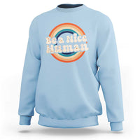 Light blue crewneck sweatshirt with 'Be a Nice Human' rainbow graphic