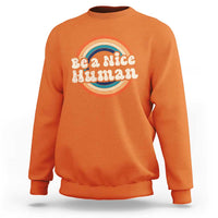 Orange crewneck sweatshirt with 'Be a Nice Human' rainbow graphic