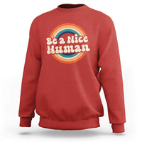 Red crewneck sweatshirt with 'Be a Nice Human' rainbow graphic
