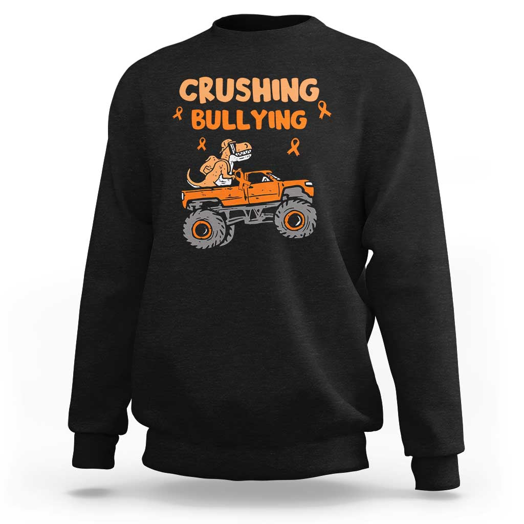 Black crewneck sweatshirt with “Crushing Bullying” dinosaur graphic and orange ribbon accents