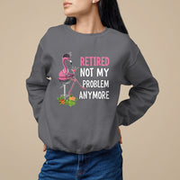 Charcoal crewneck retirement sweatshirt with pink flamingo graphic and “Retired / Not My / Problem / Anymore” text.