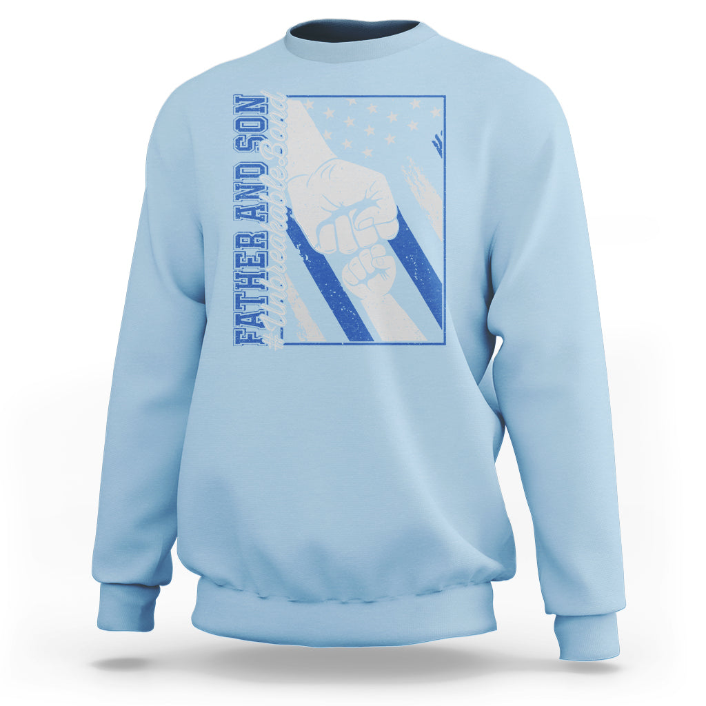 Light blue crewneck sweatshirt with blue chest graphic showing two fists and stars.