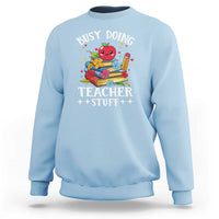 Light blue crewneck sweatshirt with colorful “Busy Doing Teacher Stuff” graphic on chest.