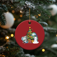 Red round axolotl Christmas ornament with tree scene, gold hanging loop on pine