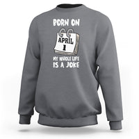 Charcoal gray crewneck sweatshirt with "Born on April 1" joke text graphic on chest