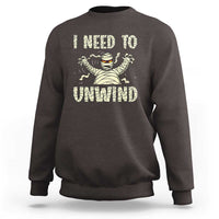 Dark brown Halloween mummy sweatshirt with 'I need to unwind' graphic on chest