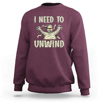 Maroon Halloween mummy sweatshirt with 'I need to unwind' graphic on chest