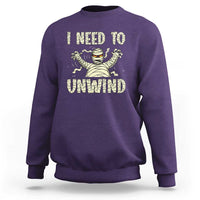 Purple Halloween mummy sweatshirt with 'I need to unwind' graphic on chest