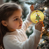 Gold round Christmas ornament with ghost and Christmas tree graphic, held near an evergreen