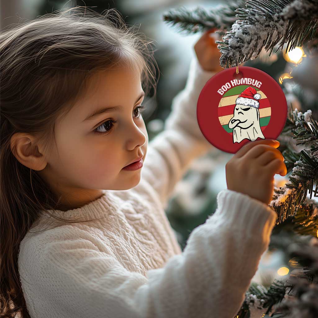 Red round “BOO HUMBUG” ghost ornament held near a Christmas tree