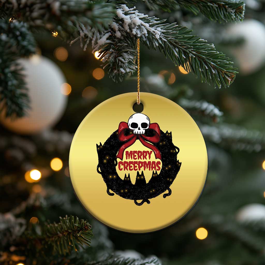 Gold round cat-wreath ornament hanging on evergreen, skull “Merry Creepmass” design