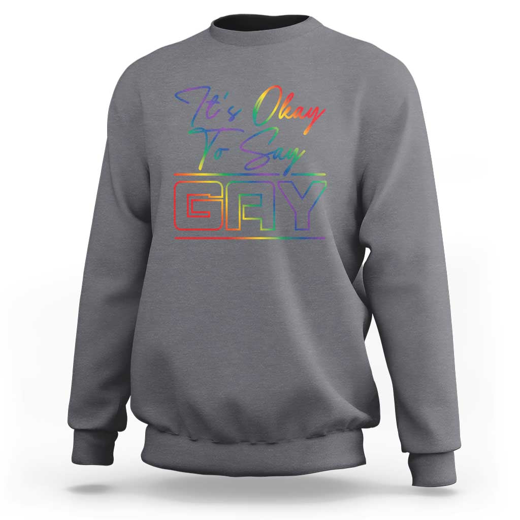 Charcoal gray crewneck sweatshirt with colorful “It’s Okay To Say Gay” graphic