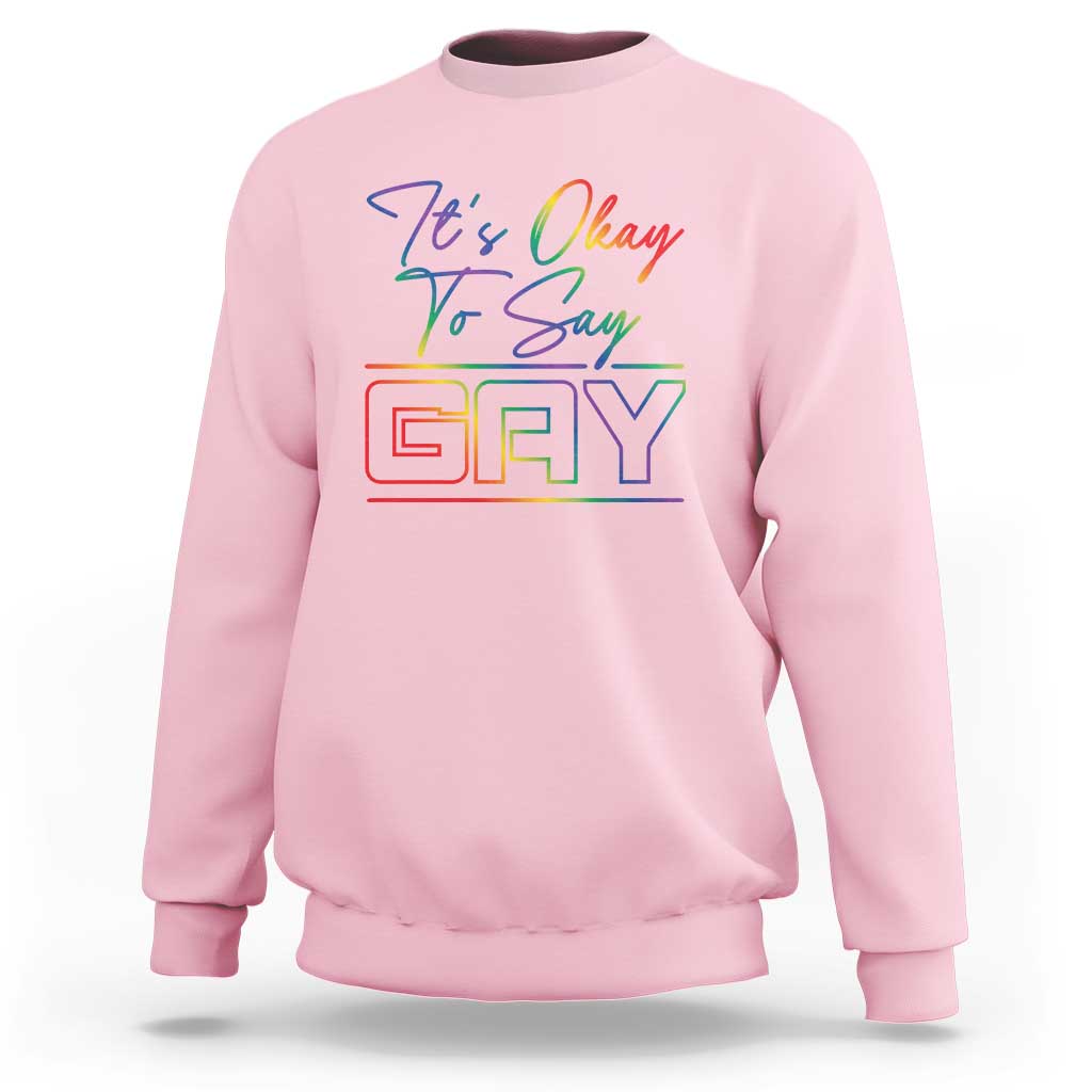 Light pink crewneck sweatshirt with colorful “It’s Okay To Say Gay” graphic