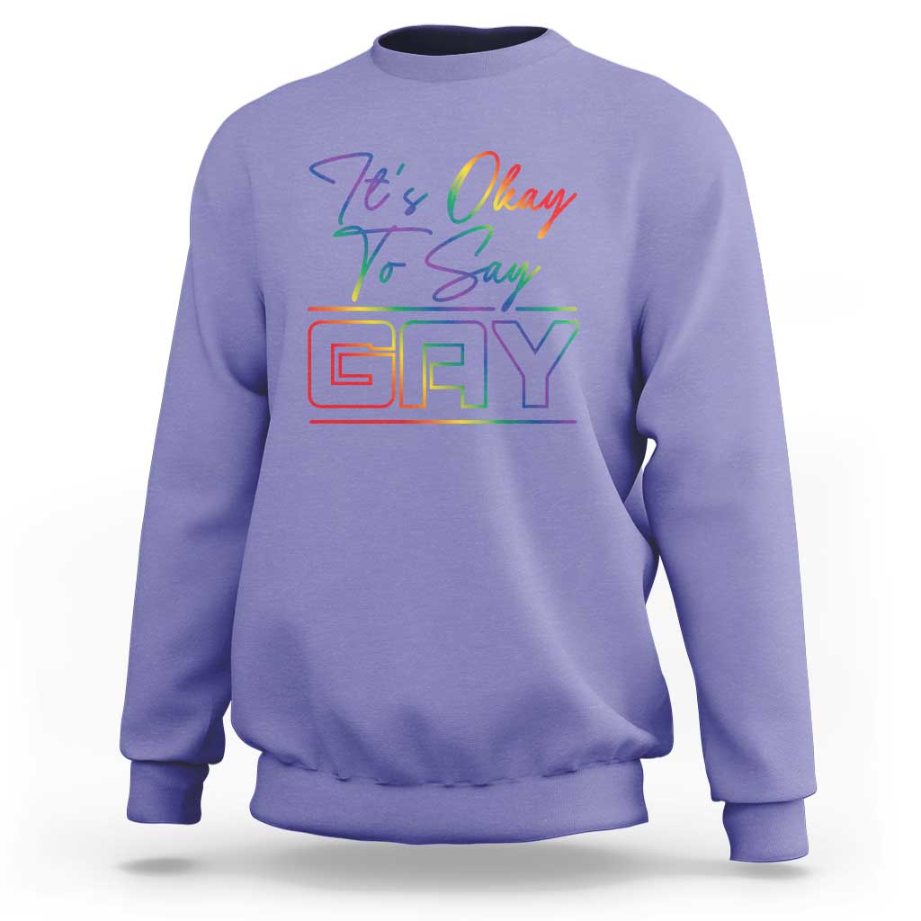 Light purple crewneck sweatshirt with colorful “It’s Okay To Say Gay” graphic