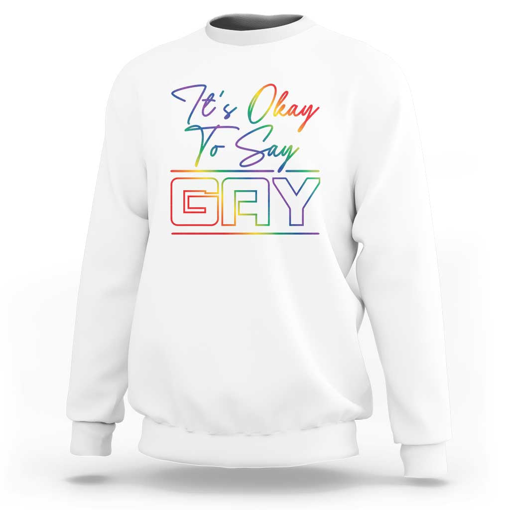White crewneck sweatshirt with colorful “It’s Okay To Say Gay” graphic