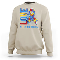 Light beige autism awareness sweatshirt with puzzle heart graphic and “NEEDS NO WORDS” text