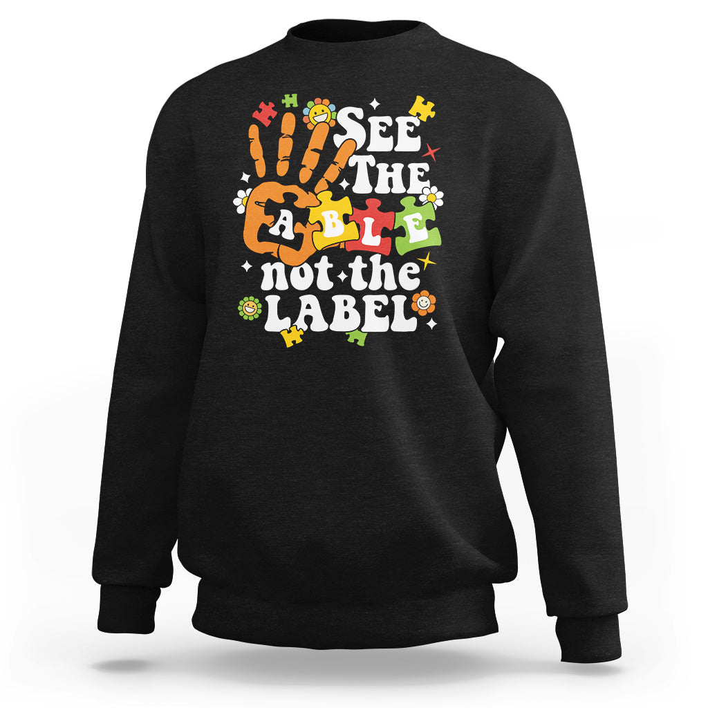 Black autism awareness sweatshirt with colorful “See the able not the label” graphic.