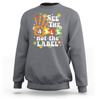 Charcoal gray autism awareness sweatshirt with colorful “See the able not the label” graphic.
