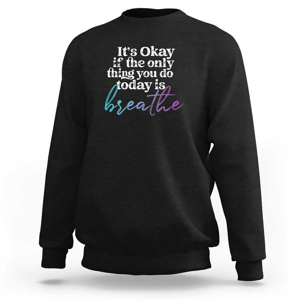 Black crewneck sweatshirt with front text "It's Okay" and "breathe" graphic