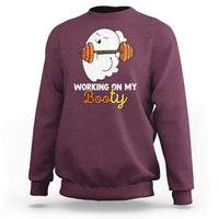 Maroon crewneck sweatshirt with ghost lifting barbell graphic and “Working on My Booty” text