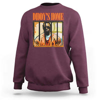 Maroon crewneck sweatshirt with “DIDDY’S HOME” graphic and portrait print on chest.