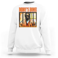 White crewneck sweatshirt with “DIDDY’S HOME” graphic and portrait print on chest.
